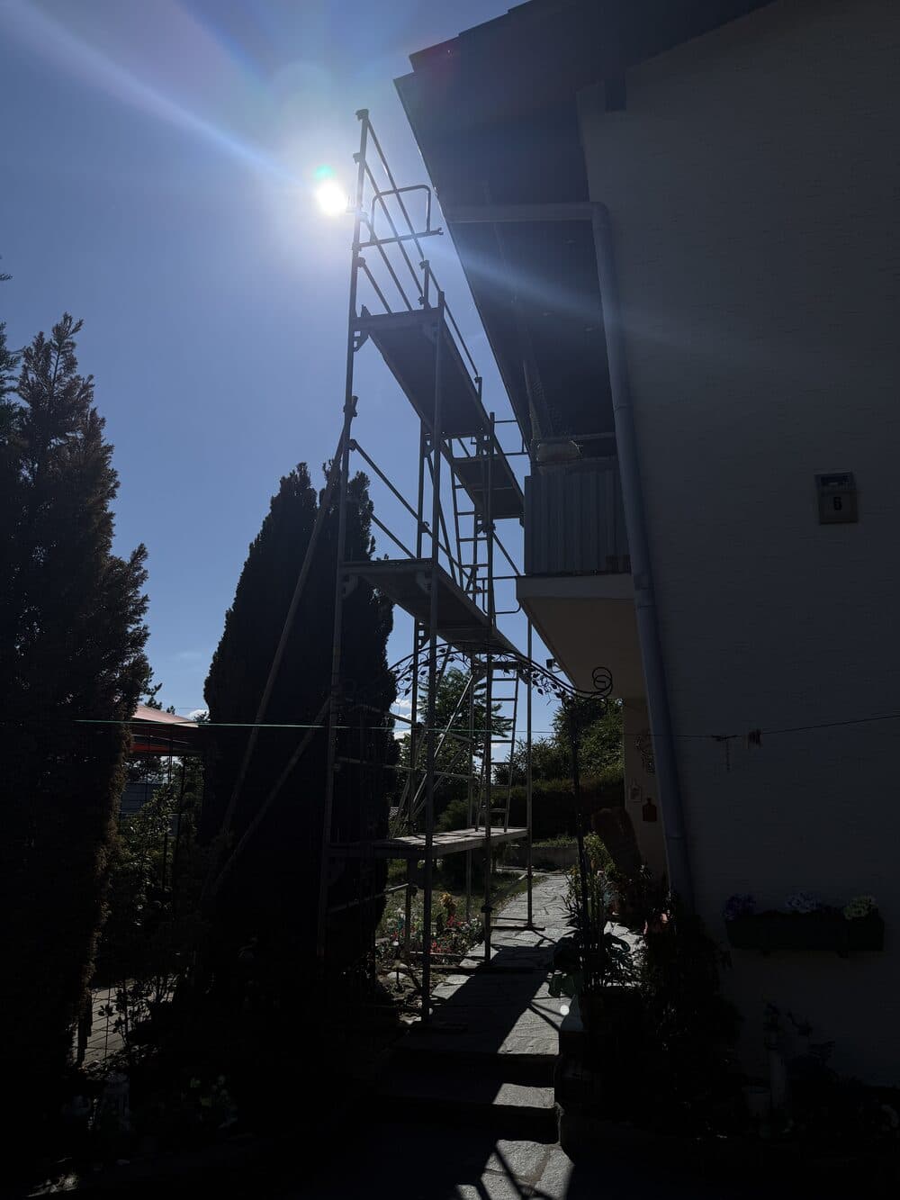 Gerüst am Haus für die Montage eines Balkonkraftwerks auf dem Dach, im Gegenlicht der Sonne