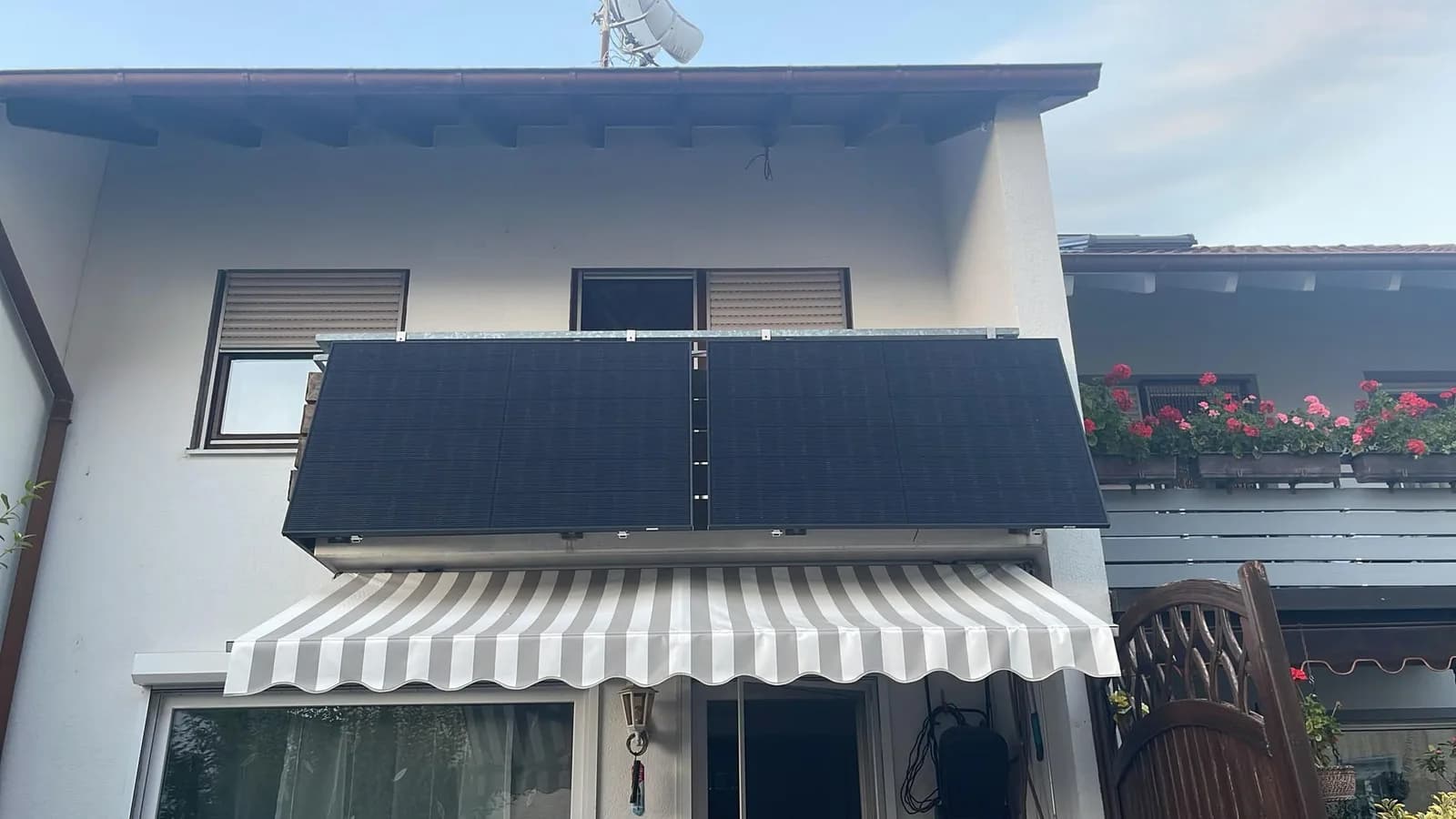 Zwei Solarmodule an einem Balkongeländer über einer Markise